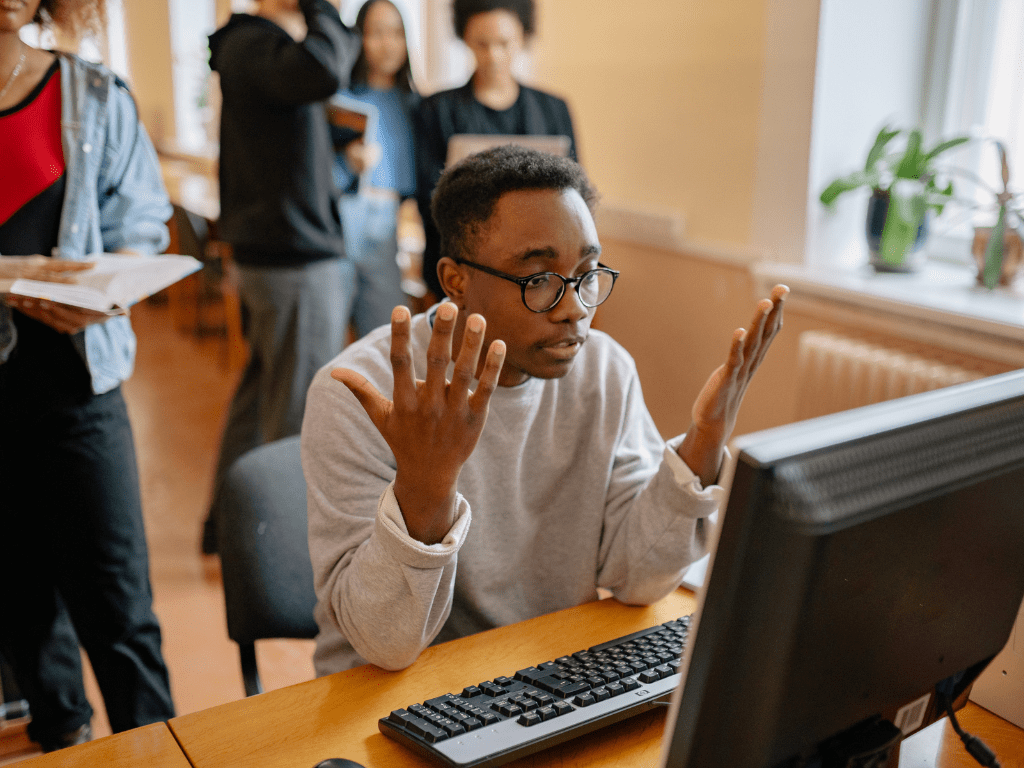 Man looking confused while sitting in front of a computer and wondering about a problem.