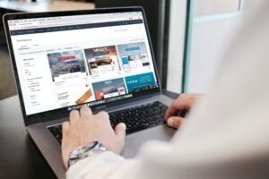 Person using a laptop to browse website templates for web design inspiration.